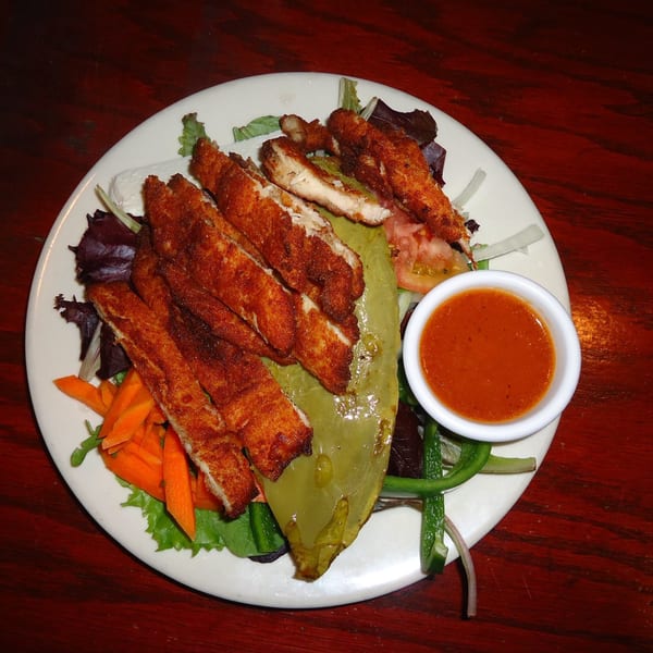 A Noche Mexicana dish with breaded chicken strips, salad, and a side of red sauce.